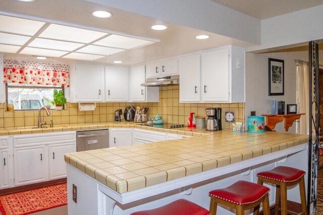 kitchen featuring sink, white cabinetry, stainless steel dishwasher, and tile counters