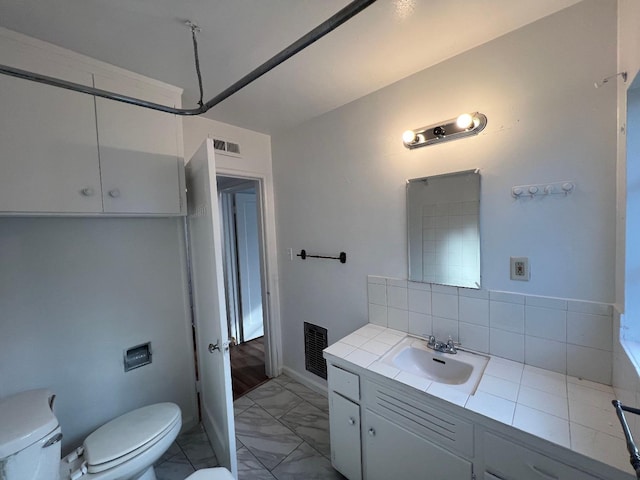 bathroom with vanity, decorative backsplash, and toilet