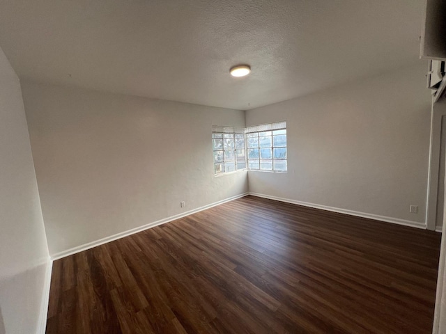 empty room with dark wood-type flooring and a textured ceiling