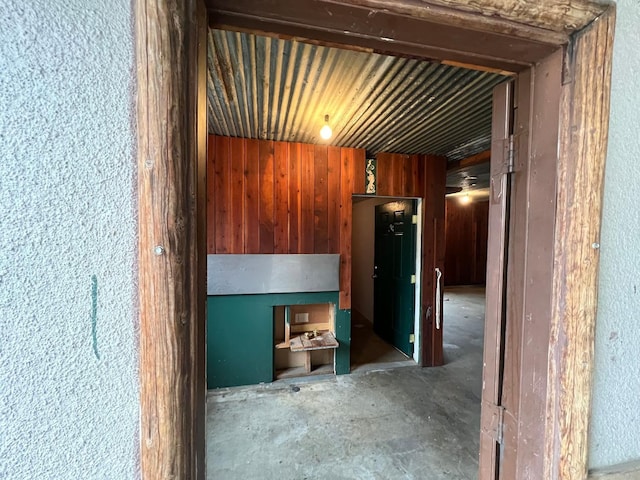 corridor featuring wooden walls and concrete flooring