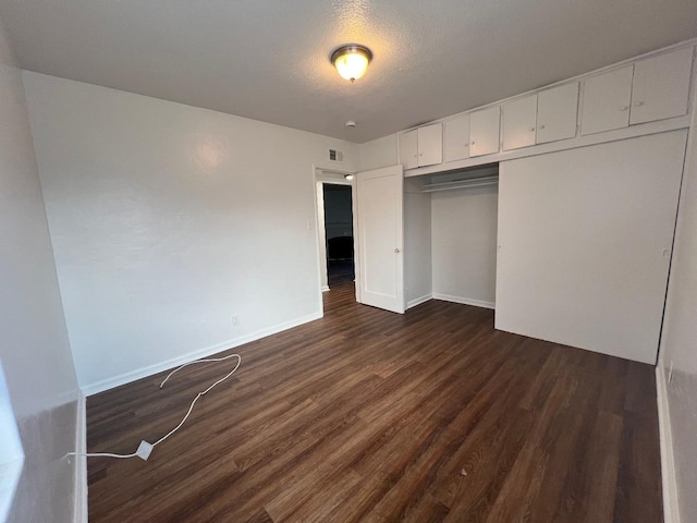 unfurnished bedroom with dark wood-type flooring, a closet, and a textured ceiling