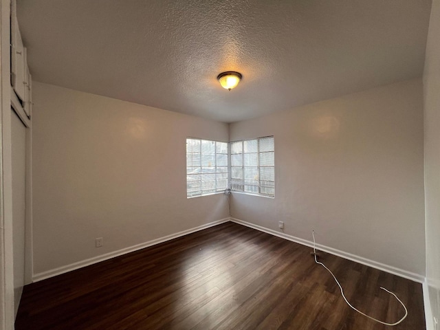 spare room featuring dark wood-type flooring and a textured ceiling