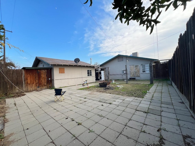 rear view of property with a patio area and a fire pit