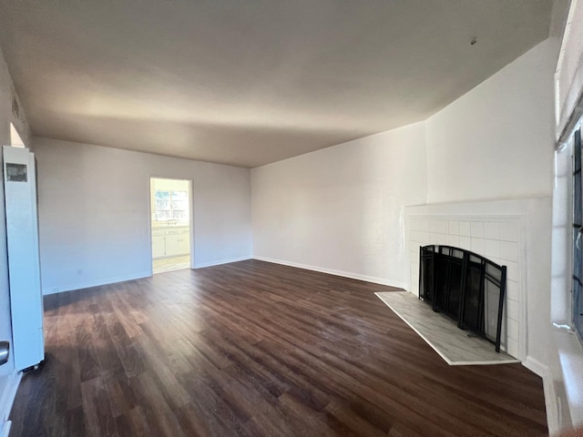 unfurnished living room with dark hardwood / wood-style flooring and a tile fireplace