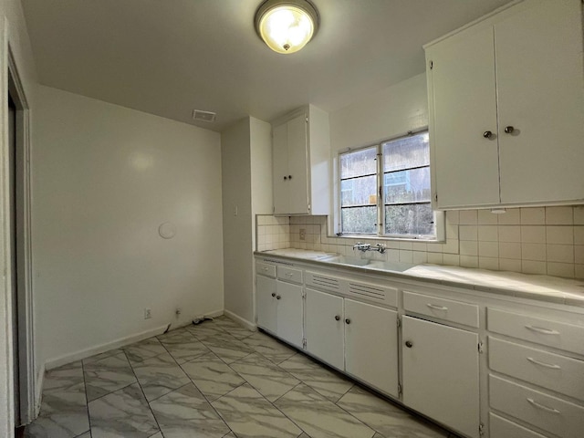 kitchen with sink, decorative backsplash, and white cabinets