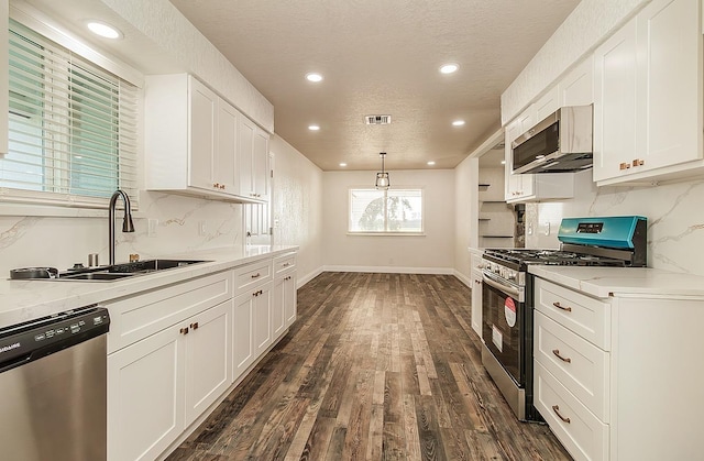 kitchen featuring white cabinetry, sink, hanging light fixtures, light stone counters, and stainless steel appliances