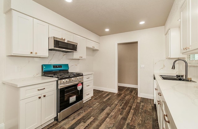 12027 S Brawley Ave, Caruthers, CA 93609 - kitchen with stainless steel appliances, a sink, dark wood-style flooring, light stone counters, and white cabinetry
