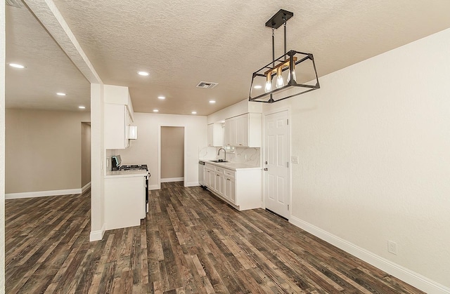 kitchen featuring white cabinetry, sink, backsplash, gas range, and dark wood-type flooring