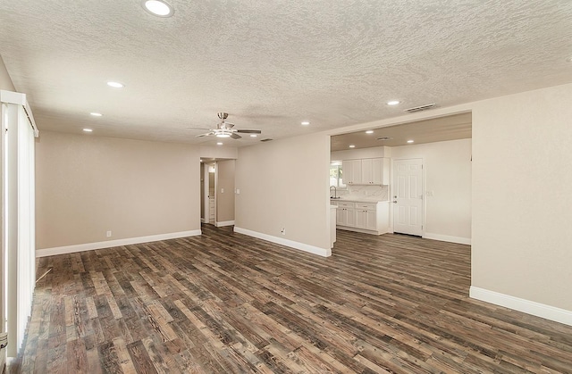 unfurnished living room with sink, a textured ceiling, dark wood-type flooring, and ceiling fan