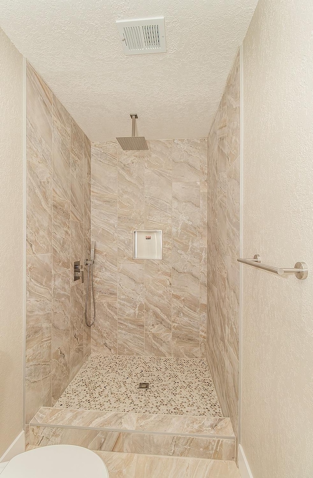 12027 S Brawley Ave, Caruthers, CA 93609 - full bath with a tile shower, a textured ceiling, toilet, and baseboards