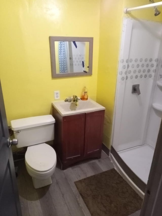 bathroom with hardwood / wood-style flooring, toilet, vanity, and walk in shower