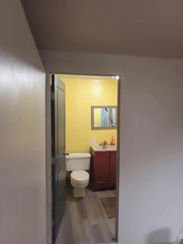bathroom featuring wood-type flooring, vanity, and toilet