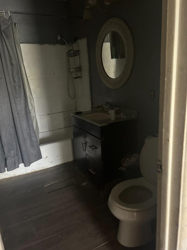 full bathroom with hardwood / wood-style floors, vanity, shower / tub combo, and toilet
