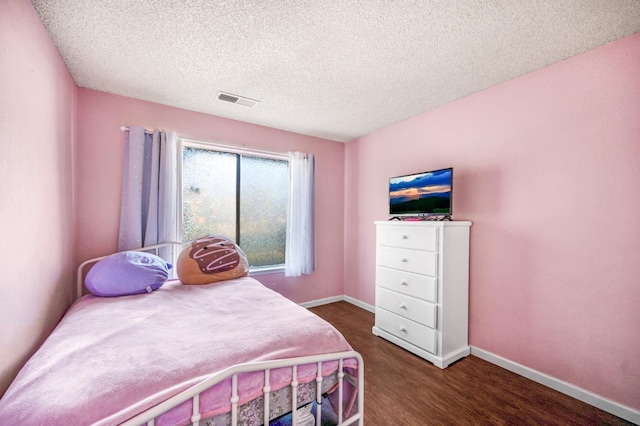 bedroom with a textured ceiling and dark wood-type flooring