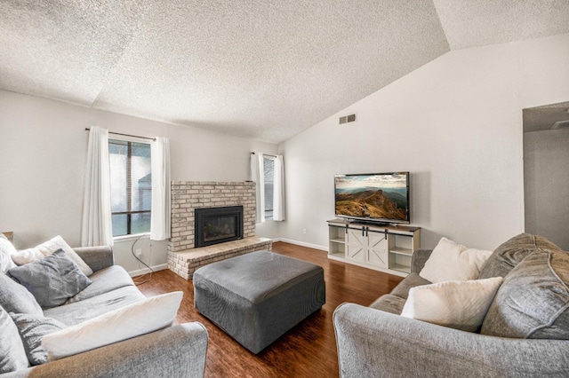 living room featuring a textured ceiling, dark hardwood / wood-style flooring, a fireplace, and vaulted ceiling