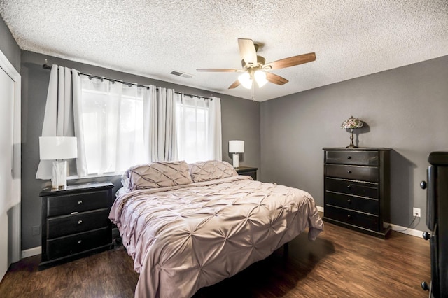 bedroom with ceiling fan, dark wood-type flooring, and a textured ceiling