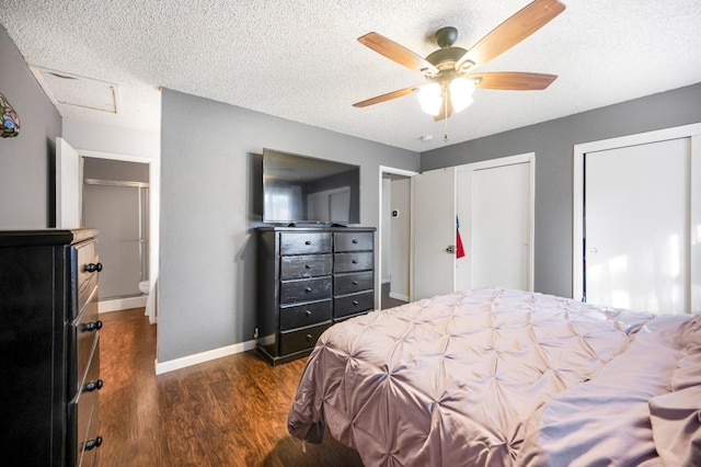 bedroom with connected bathroom, multiple closets, ceiling fan, dark wood-type flooring, and a textured ceiling