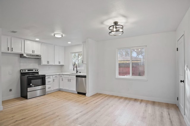 kitchen with stainless steel appliances, visible vents, backsplash, a sink, and under cabinet range hood