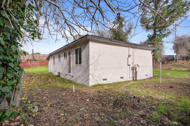 view of property exterior featuring crawl space, fence, and stucco siding