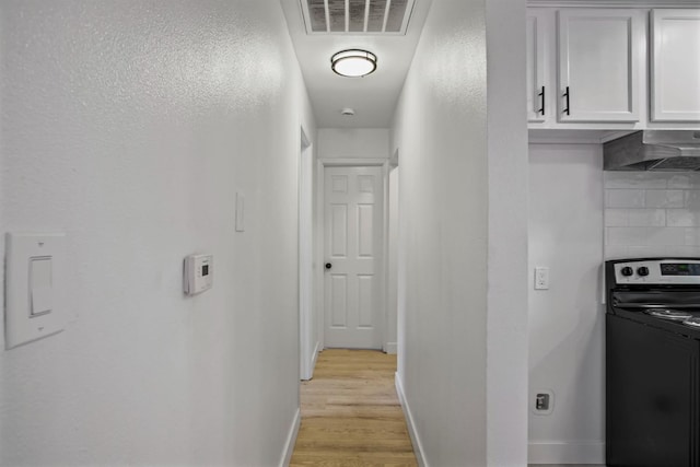 hallway featuring light wood-type flooring, visible vents, and baseboards