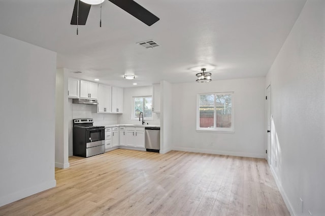 kitchen featuring visible vents, decorative backsplash, appliances with stainless steel finishes, white cabinetry, and a sink