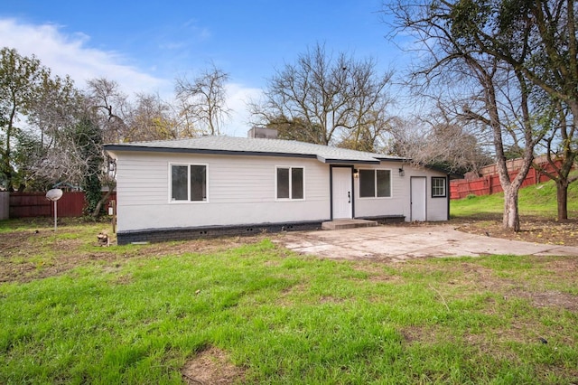 rear view of property featuring a patio area, fence, a lawn, and roof with shingles