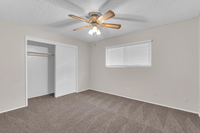 unfurnished bedroom with ceiling fan, dark carpet, a textured ceiling, and a closet