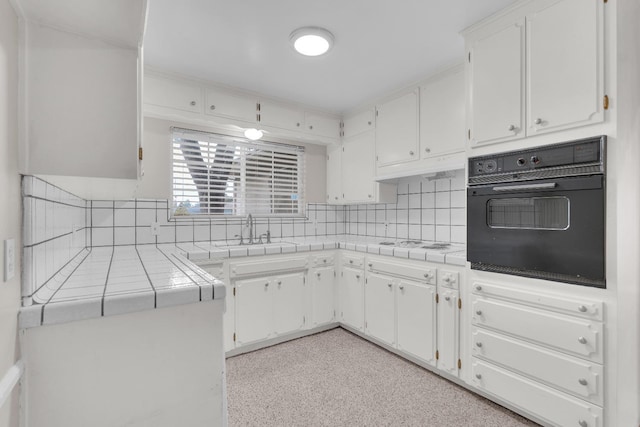 kitchen featuring tile countertops, white cabinetry, sink, and oven