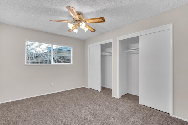 unfurnished bedroom featuring carpet flooring, a textured ceiling, ceiling fan, and multiple closets