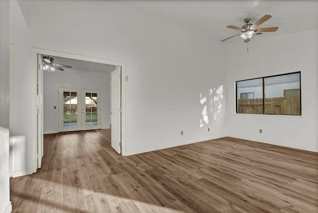 empty room with french doors, baseboards, wood finished floors, and a ceiling fan