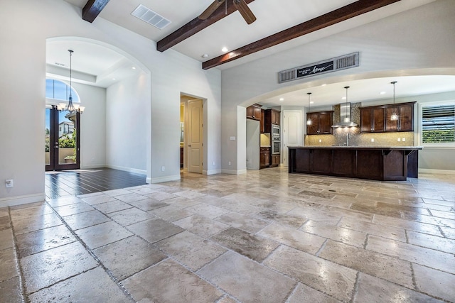 10810 N Matus Ave, Fresno, CA 93730 - unfurnished living room with visible vents, arched walkways, beam ceiling, baseboards, and stone tile floors
