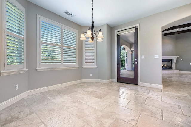 10810 N Matus Ave, Fresno, CA 93730 - unfurnished dining area with a lit fireplace, visible vents, baseboards, a notable chandelier, and stone tile floors