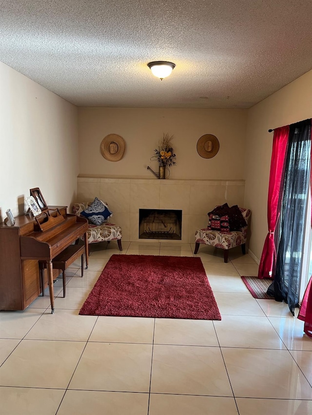 sitting room with light tile patterned floors, a textured ceiling, and a tile fireplace