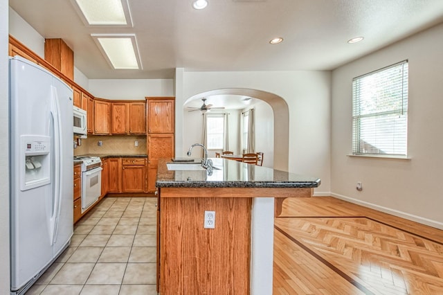 kitchen featuring white appliances, an island with sink, ceiling fan, and sink