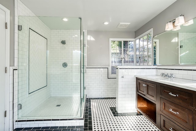 bathroom with tile patterned flooring, vanity, an enclosed shower, and tile walls