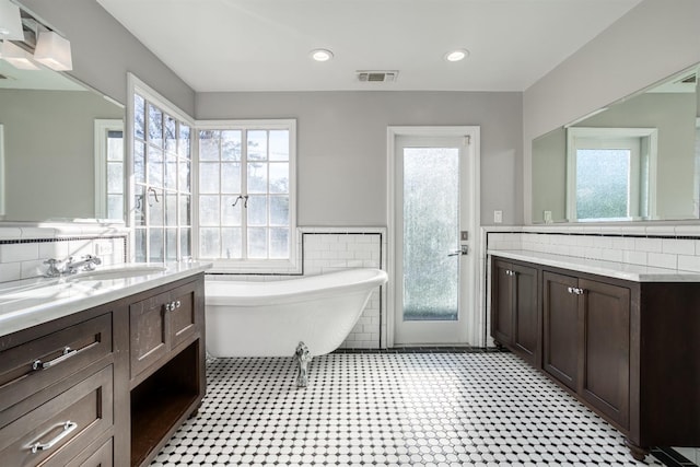 bathroom featuring a washtub, vanity, a healthy amount of sunlight, and tile walls