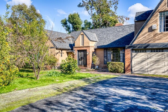 3628 N Van Ness, Fresno, CA 93704 - tudor house featuring a garage, driveway, brick siding, and a shingled roof