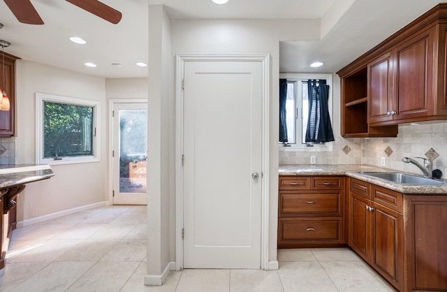 kitchen featuring tasteful backsplash, light stone countertops, sink, and light tile patterned floors