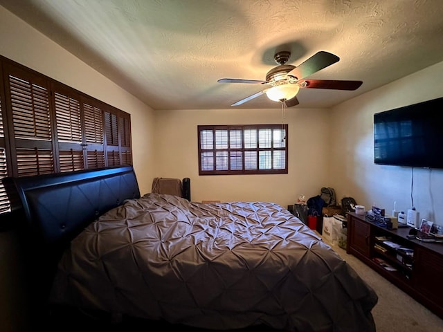 carpeted bedroom with ceiling fan and a textured ceiling