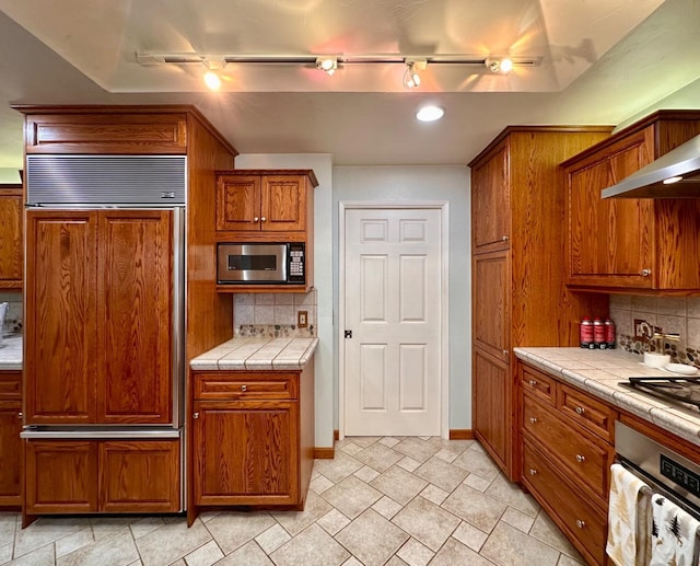 kitchen featuring backsplash, tile counters, and stainless steel appliances