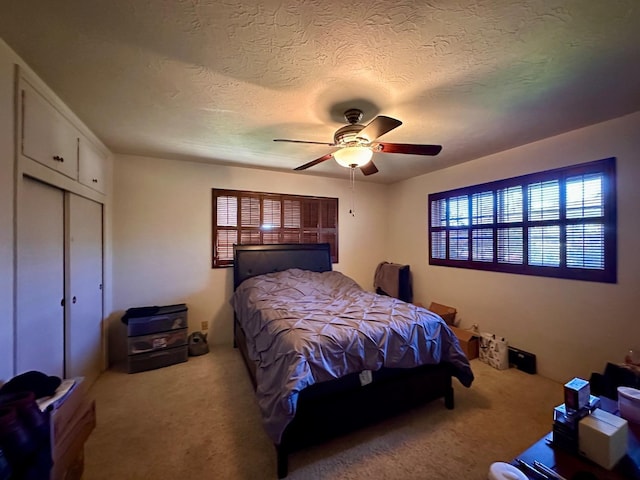 carpeted bedroom featuring a textured ceiling, ceiling fan, and a closet