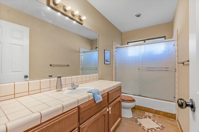 full bathroom featuring tile patterned floors, vanity, toilet, and enclosed tub / shower combo