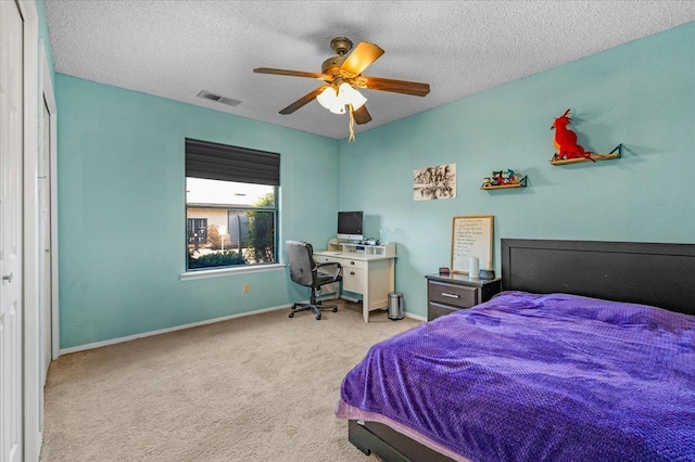 bedroom with ceiling fan, light carpet, and a textured ceiling