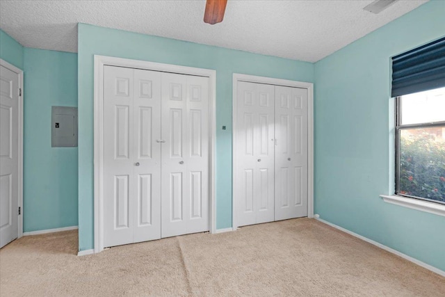 unfurnished bedroom featuring multiple closets, ceiling fan, electric panel, and a textured ceiling