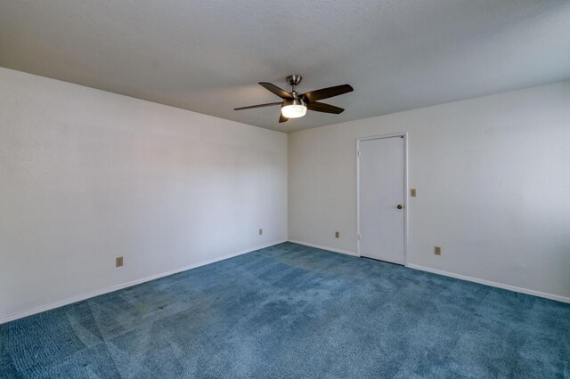 spare room featuring ceiling fan and dark carpet