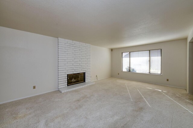 unfurnished living room with light carpet, a fireplace, and a textured ceiling