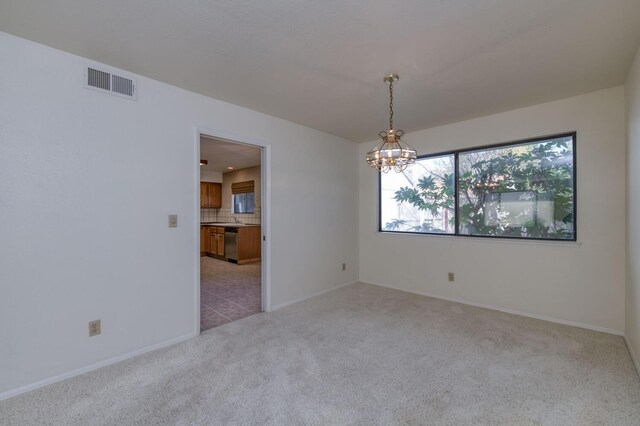 carpeted empty room with a notable chandelier