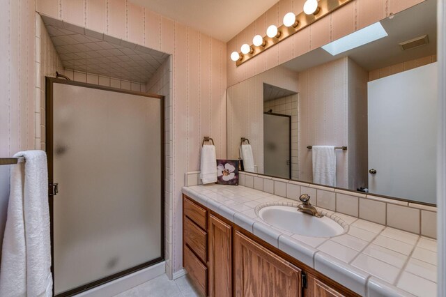 bathroom featuring vanity, a skylight, and a shower with door