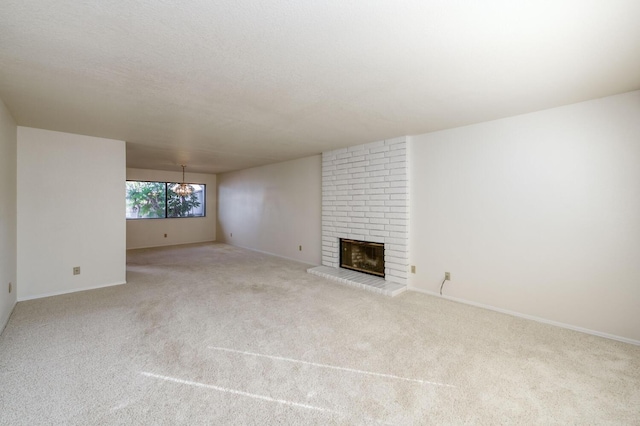 unfurnished living room featuring light carpet, a brick fireplace, and a textured ceiling