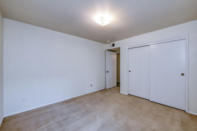 unfurnished bedroom featuring light colored carpet and a closet